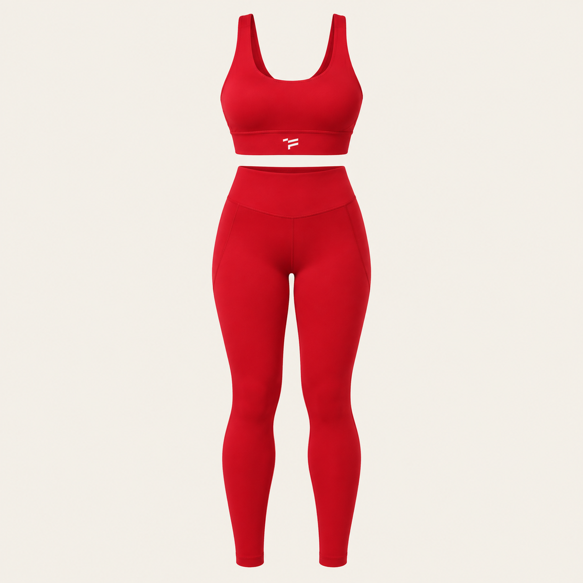 A red two-piece activewear set consisting of a scoop-neck sports bra and high-waisted leggings, shown on a neutral light beige background.