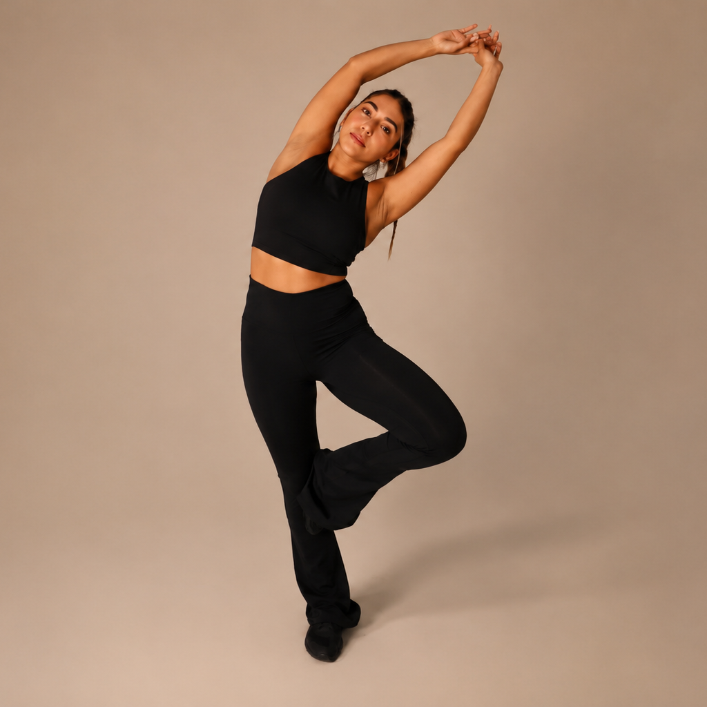 Woman in black athletic wear posing against a beige background