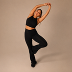 Woman in black athletic wear posing against a beige background